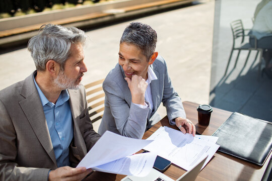 Colleagues reviewing financial documents at an outdoor meeting