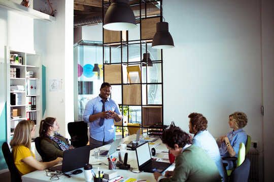 Man presenting to colleagues in a casual office meeting