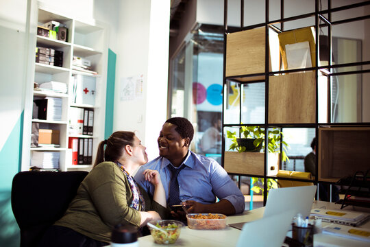 Coworkers flirting during lunch break at office desk