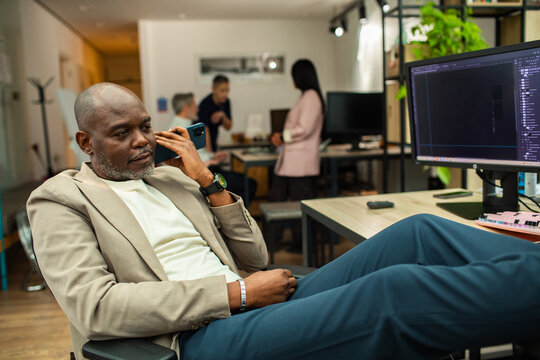 Businessman taking a phone call with feet up at desk