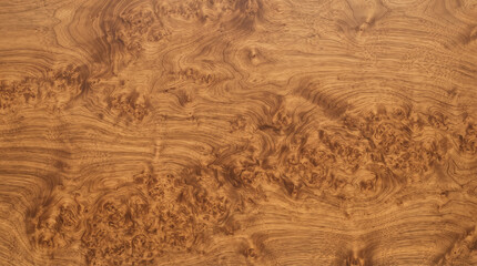 Fototapeta premium Close-up of a warm brown wooden surface with intricate burl grain patterns, showing natural textures and organic shapes suitable for backgrounds.