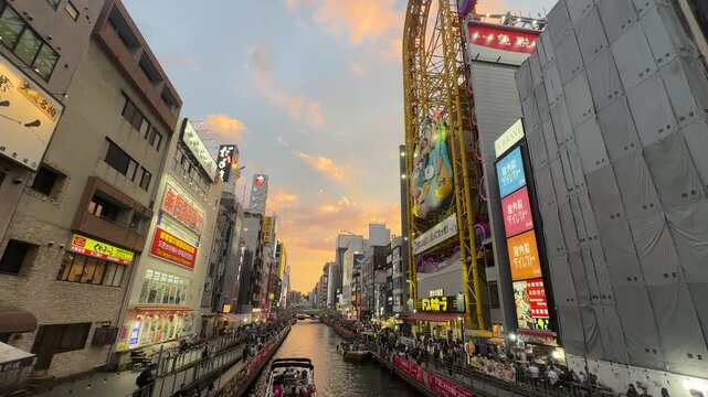 Dotonbori Canal in Osaka, Japan, featuring the riverside promenade, sightseeing boats and brightly illuminated commercial signs along the famous entertainment district.