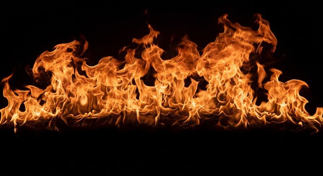 Fire spreads widely across the frame, displaying intense orange and yellow hues against a stark black background.