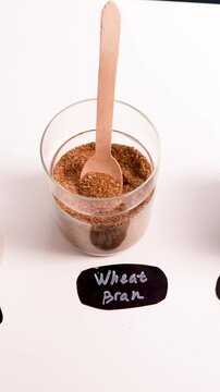 Row of glass jars with psyllium husk, chia seeds, flax seeds and wheat bran