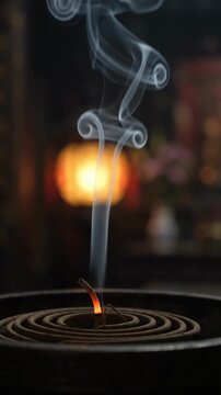 Incense coil smoke curling in temple gloom macro