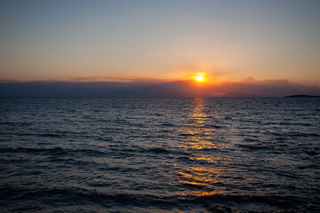 Obraz premium Sun setting behind distant islands on the Aegean Sea horizon