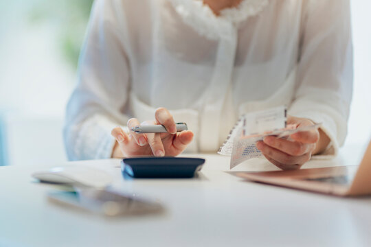 A mother in her home office reviews annual expenses and taxes, balancing family budgeting and investments.