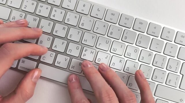 Journalism text typing on a white keyboard by a reporter developing a news story. Creative writer drafts content on a minimalist tabletop using high speed touch typing. Top down perspective