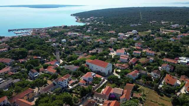 A breathtaking aerial drone panorama of old village on Silba Island, Croatia. The shot showcases the vibrant turquoise harbor, a docked ferry, and the charming coastal village stretching across the