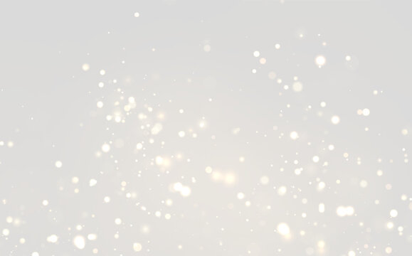 Floating golden particles create a shimmering bokeh effect on a dark background. The lights vary in size and intensity, scattered throughout the frame.