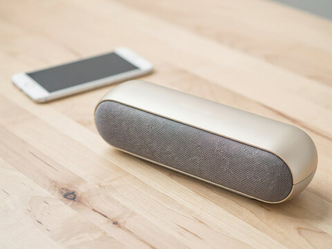 Wireless portable speaker being used on a wooden surface with copy space