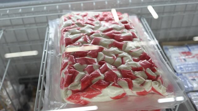Frozen imitation crab sticks are vacuum sealed in a large package inside a supermarket freezer offering convenient seafood for salads sushi snacks and home cooking
