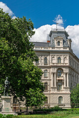 Eclectic facade of Hubner Court with a corner tower and bronze statue partly hidden by trees in Budapest © Guillaume Angleraud