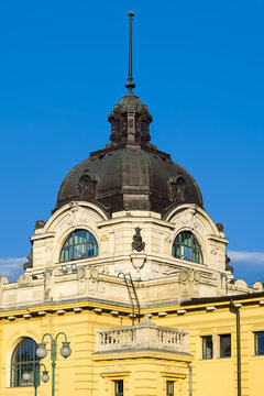Twin oval windows flank a decorated dome pinnacle atop the Sz&eacute;chenyi bath house tower in Budapest, Hungary today
