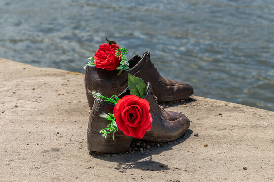 Two iron shoes with red roses and green leaves on the stone edge of the Danube embankment in Budapest, Hungary