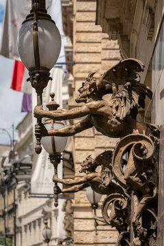 Winged imp sculptures holding globe lamps on a stone facade at the New York Cafe building in Budapest, Hungary