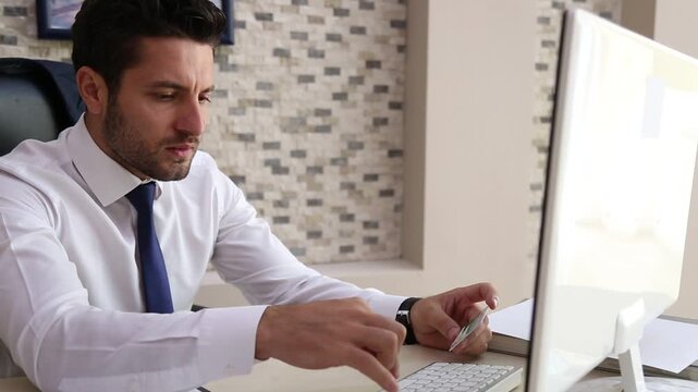 Businessman Entering Credit Card Information on Computer