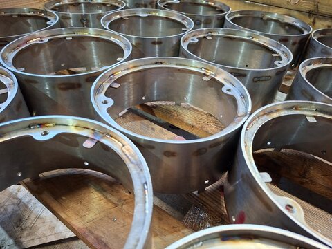 Stainless steel cylindrical metal components with welded flanges stacked on pallet