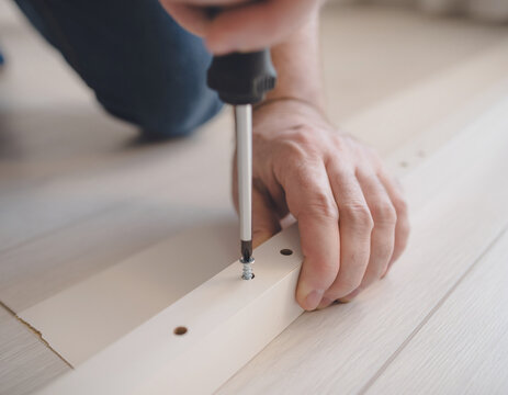 Hands assembling flat-pack furniture with screwdriver