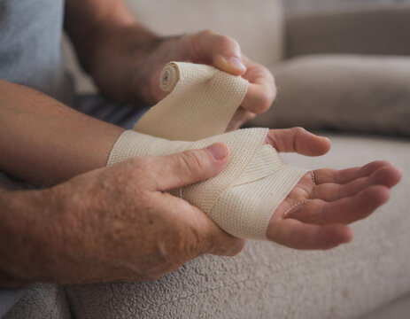 Hands wrapping elastic bandage around injured wrist