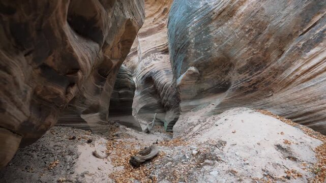 Pov moving slowly through narrow, winding slot canyon, showcasing the beautiful striped patterns and smooth, eroded textures of the sedimentary sandstone rock walls. Hiking in smooth and wavy canyon