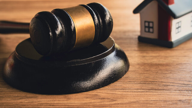 Wooden judge gavel and house model on desk for real estate law concept