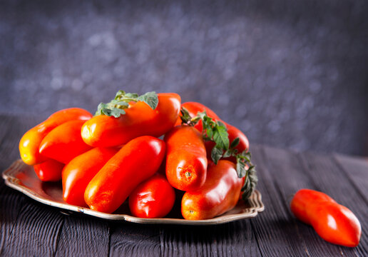 Fresh red tomatoes on plate and on wooden table