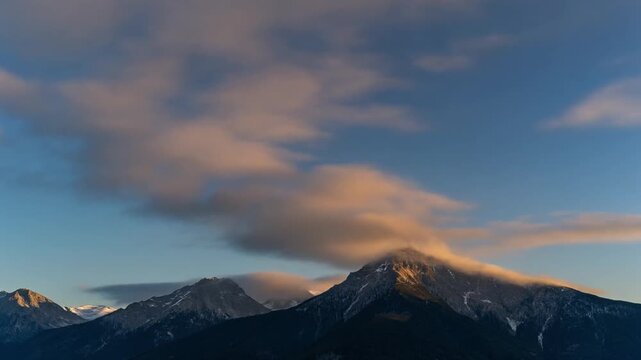 Dramatic Sunset Clouds Over Snow-Capped Mountain Peaks