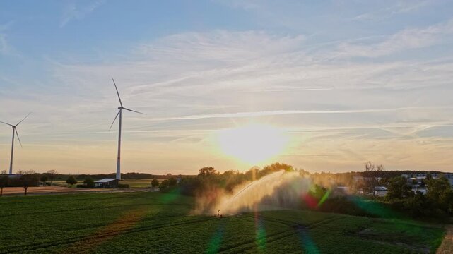 Wind mill for renewable electric energy production. Irrigation system and windmill in rural area. Agriculture irrigation. Cultivation and harvest. Organic harvest in farm field