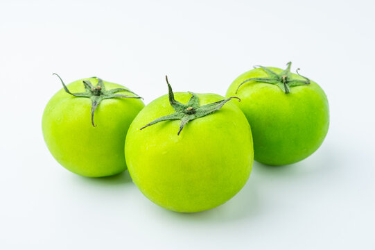Fresh green tomatoes on a white background