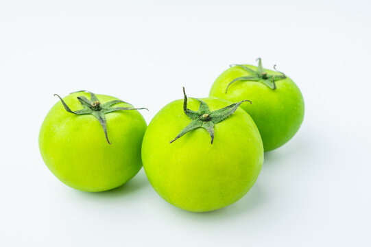 Fresh green tomatoes on a white background