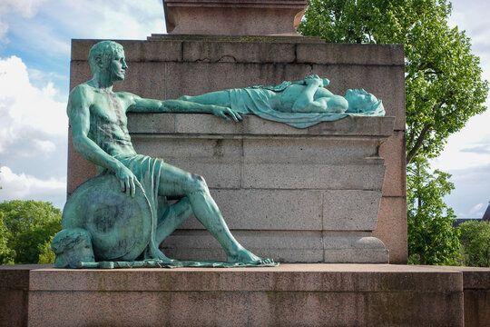 The bronze sculpture group at the base of the G&euml;lle Frau war memorial in Luxembourg City, depicting a seated bronze soldier mourning a fallen comrade lying atop a stone plinth.
