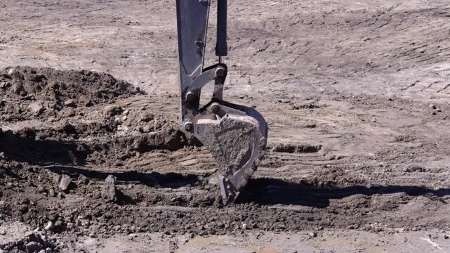Raw industrial power meets stubborn, saturated soil; thick mud clings to the bucket as the machine wrestles the unyielding terrain