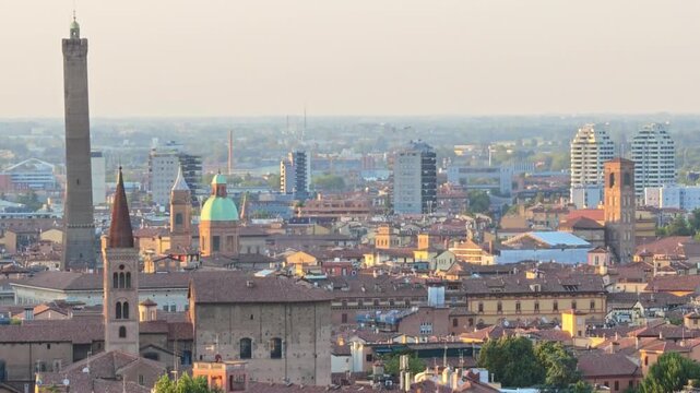 Bologna's historic downtown panorama in Italy, featuring iconic Asinelli and Garisenda towers above red-tiled rooftops and modern buildings. Basilica Saint Petronius, of Bishop patron of city.