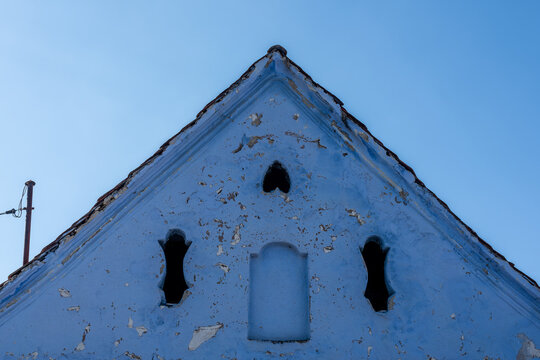 Traditional blue house gable featuring a distinctive inverted heart-shaped motif against a clear blue sky in Homorod, Romania.