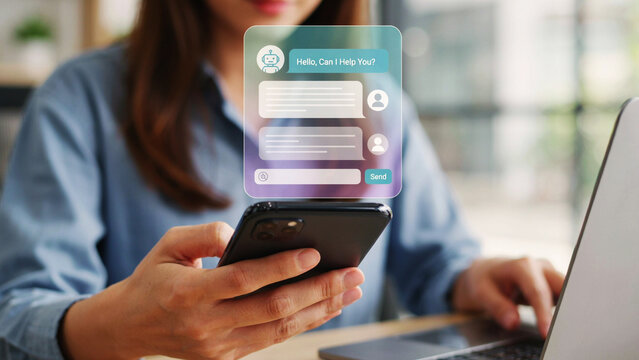Woman using smartphone with chatbot interface during remote work with laptop and soft lighting