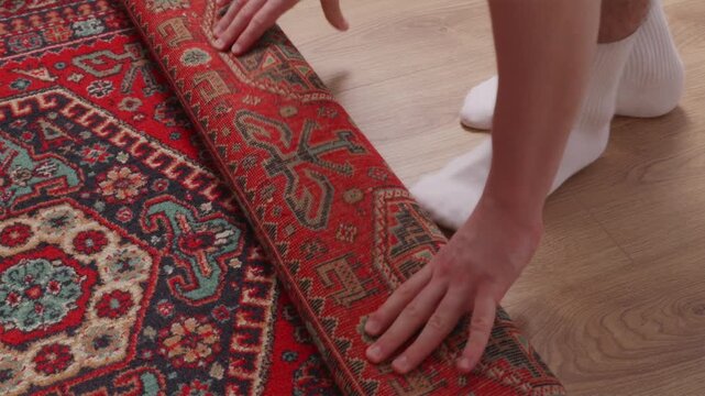 Wide shot of rolling and unrolling red rug on room floor
