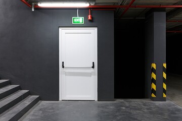 Obraz premium The Exit Door in an Industrial Parking Garage Corridor at Night