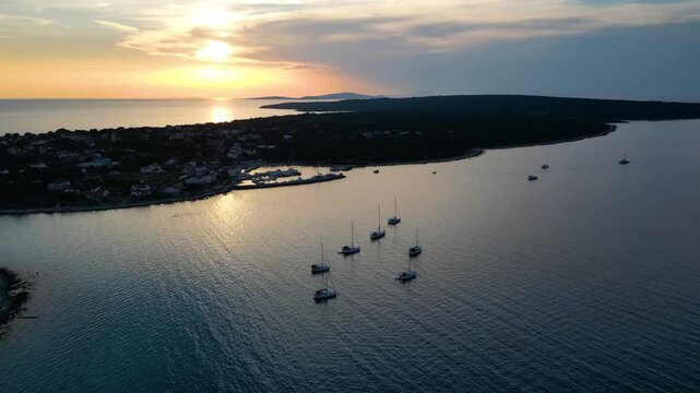A stunning aerial drone shot capturing the warm golden sunset over the Sotorisce bay and Mulj harbor area on Silba Island, Croatia. The perspective showcases the sheltered marina filled with boats