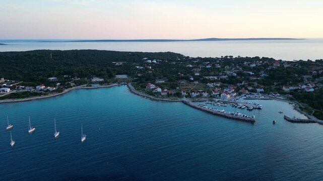 A stunning aerial drone shot capturing the warm golden sunset over the Sotorisce bay and Mulj harbor area on Silba Island, Croatia. The perspective showcases the sheltered marina filled with boats