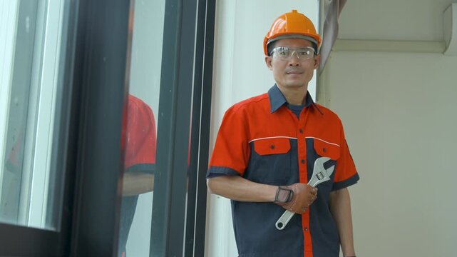 Professional construction worker holding a large adjustable wrench in a modern building interior