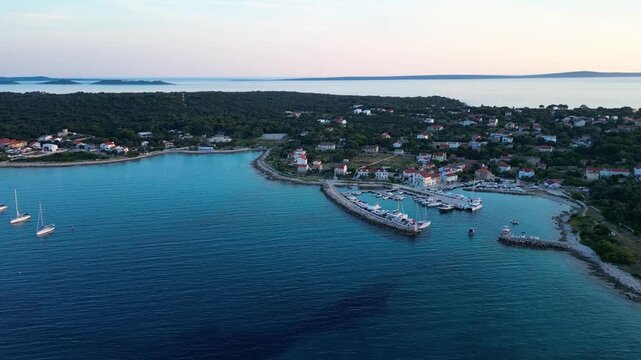 A stunning aerial drone shot capturing the warm golden sunset over the Sotorisce bay and Mulj harbor area on Silba Island, Croatia. The perspective showcases the sheltered marina filled with boats