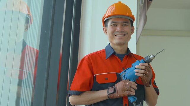 Professional construction worker holding a power drill while wearing a safety helmet and uniform