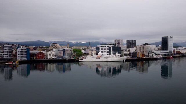Aerial view of Dupuy de Lome French navy ship docked in city harbor reflecting in calm waters in Bodo, Norway