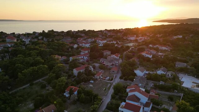 A stunning aerial drone shot capturing the warm golden sunset over the Sotorisce bay and Mulj harbor area on Silba Island, Croatia. The perspective showcases the sheltered marina filled with boats