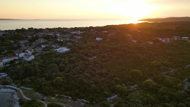 A stunning aerial drone shot capturing the warm golden sunset over the Sotorisce bay and Mulj harbor area on Silba Island, Croatia. The perspective showcases the sheltered marina filled with boats