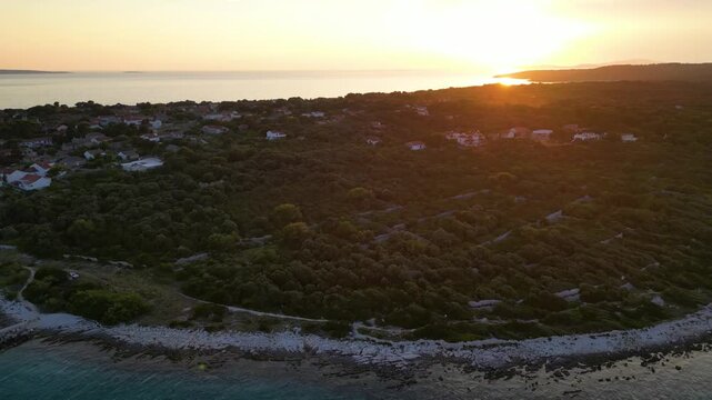 A stunning aerial drone shot capturing the warm golden sunset over the Sotorisce bay and Mulj harbor area on Silba Island, Croatia. The perspective showcases the sheltered marina filled with boats