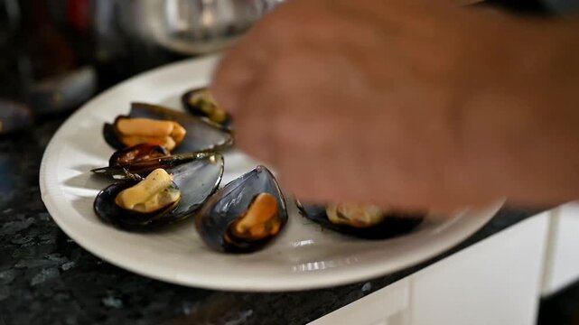 Fresh steamed mussels being arranged on a plate, Mediterranean seafood dish, food presentation, shellfish serving, traditional cuisine, fresh ingredients, homemade meal and culinary preparation