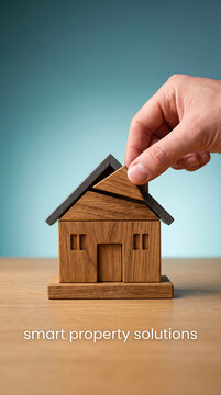 Hand placing wooden block roof on miniature house model for property solutions concept