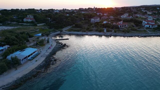 A stunning aerial drone shot capturing the warm golden sunset over the Sotorisce bay and Mulj harbor area on Silba Island, Croatia. The perspective showcases the sheltered marina filled with boats